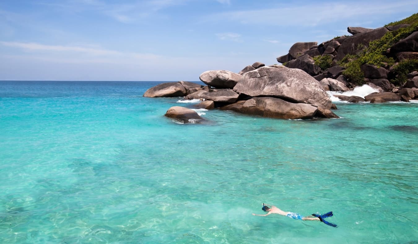 Um homem mergulha com uma máscara e um cano em águas cristalinas nas Seychelles