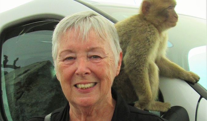 Sherrill viajante sênior com um macaco no ombro durante uma viagem ao exterior
