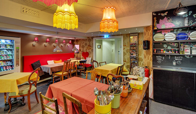 Sala de jantar eclética com muitas mesas cobertas com toalhas de mesa brilhantes e lâmpadas suspensas de cores diferentes no host Skanstull, Estocolmo