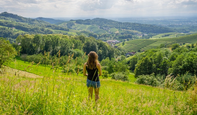 Christine Addis fica em um campo verde com vista para as colinas