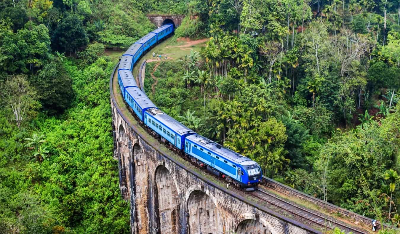 O Trem Azul passa pela histórica Ponte dos Nove Arcos, no Sri Lanka, cercada por uma selva exuberante