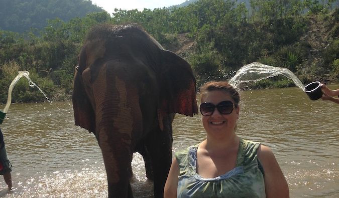 Viajante da mulher banha um elefante em Chiangmai, Tailândia