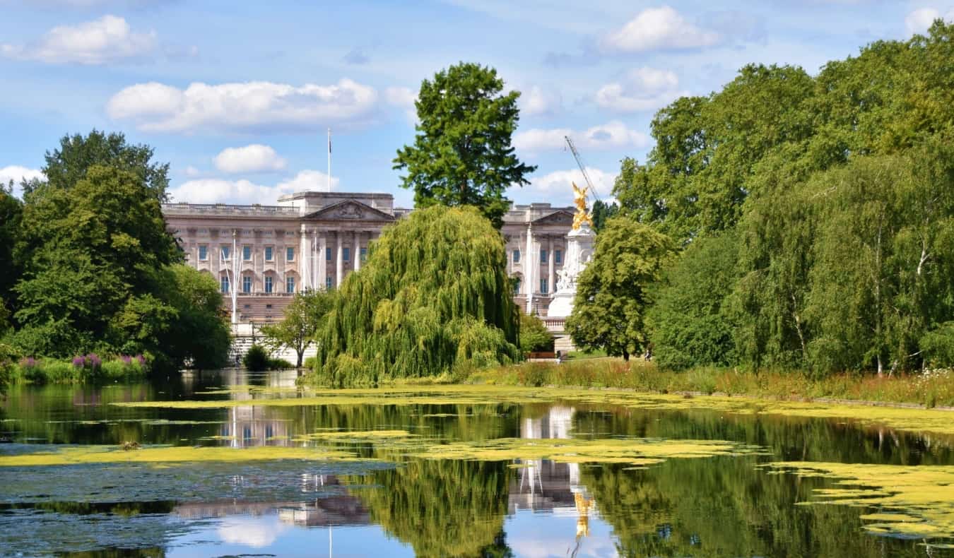 Vista do Palácio de Buckingham através das árvores e atrás do lago calmo no parque de St. James em Londres, Inglaterra