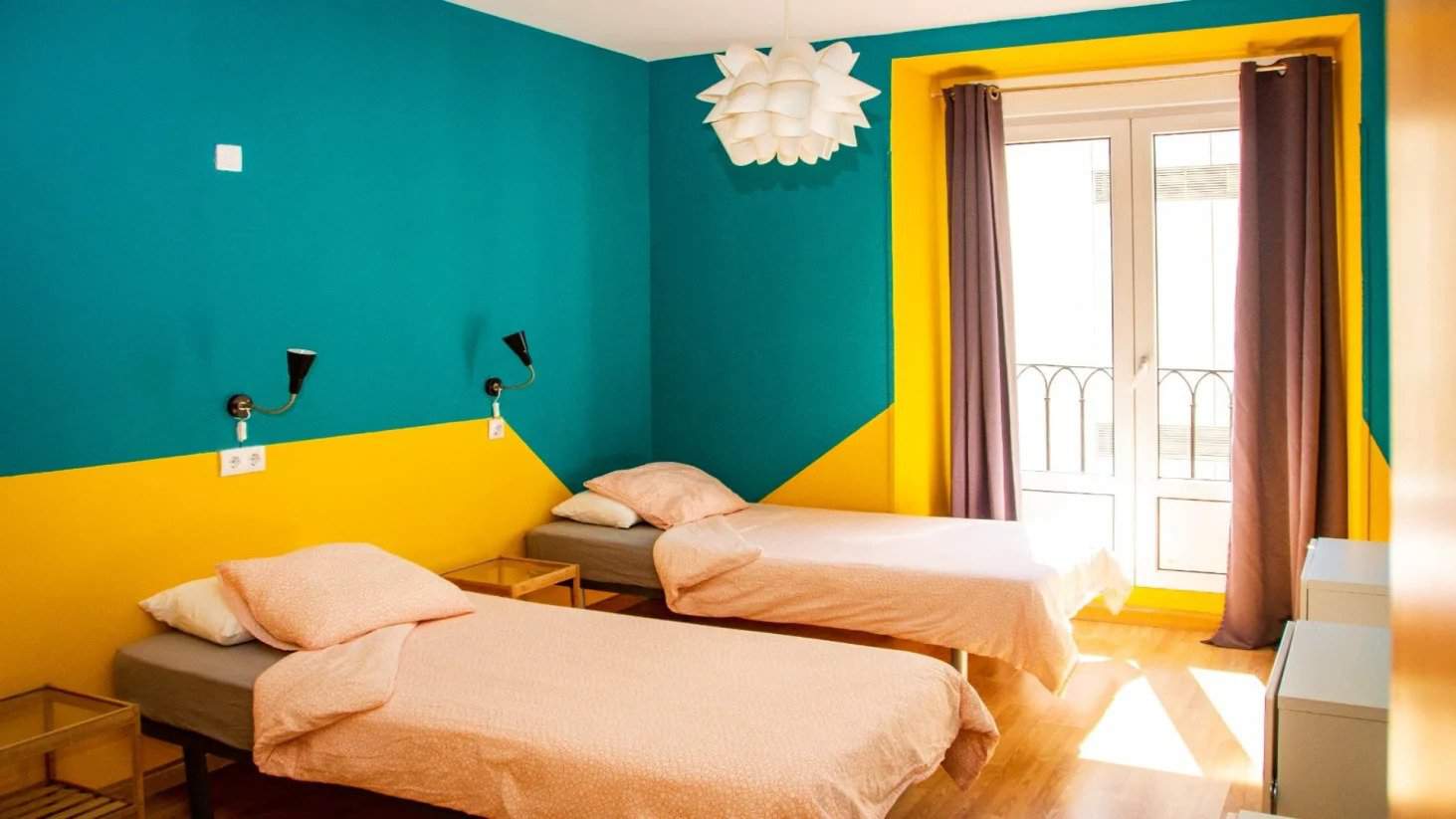 Duas camas de solteiro em um quarto colorido no Sungate One Hostel em Madrid, Espanha.