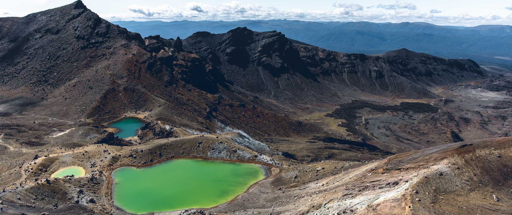 Paisagens vulcânicas dramáticas com lagos verdes brilhantes abaixo, na travessia alpina de Tumariro, perto de Taupo, Nova Zelândia