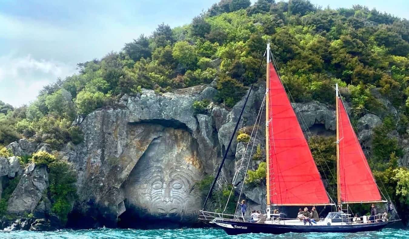 Veleiro vermelho em frente às esculturas de rochas de Maori no lago Taupo na Nova Zelândia