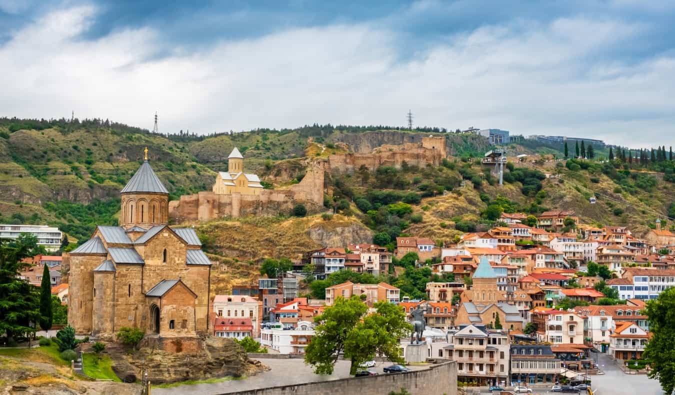 Cidade antiga de Tbilisi com casas tradicionais, diversas igrejas e muralhas que se projetam nas colinas
