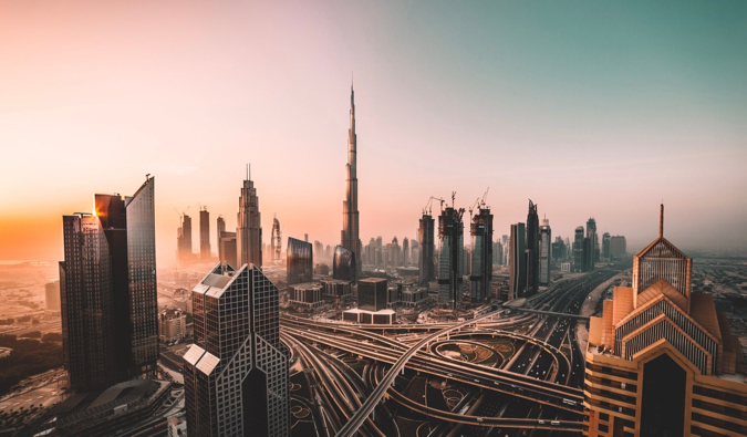 Burj Khalifa maciço e arranh a-céus ao seu redor e estradas em Dubai ao nascer do sol