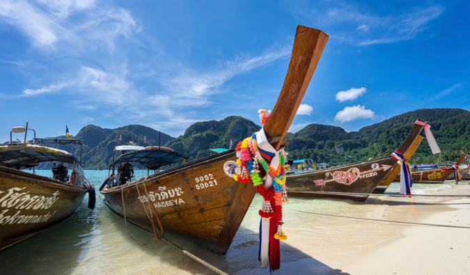Barcos de cauda longa na ilha de Koch-Pi-Pih, estacionados na areia no cenário de um céu azul brilhante na Tailândia