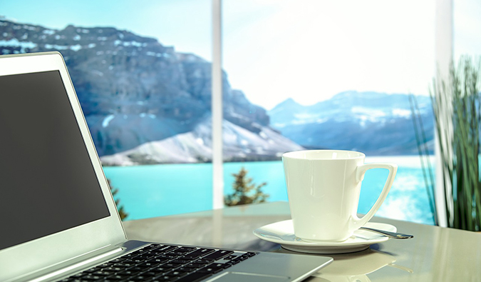 Foto de café e laptop na janela com uma vista pitoresca