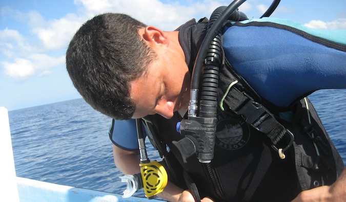Matt coloca seu equipamento para mergulhar, sentado em um barco