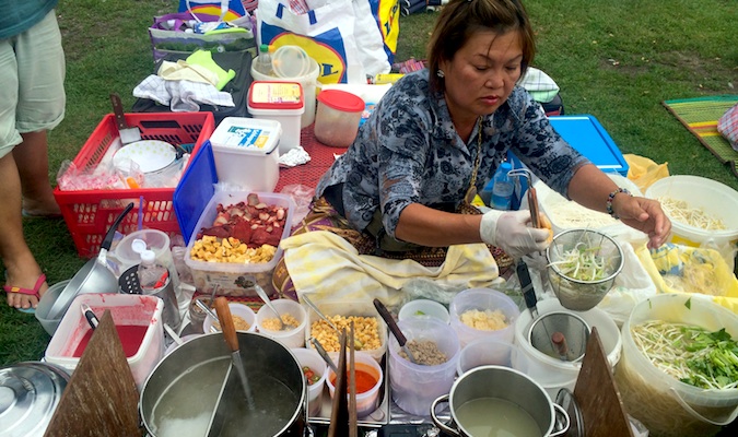 Mulher tailandesa serve comida tailandesa no mercado em Berlim