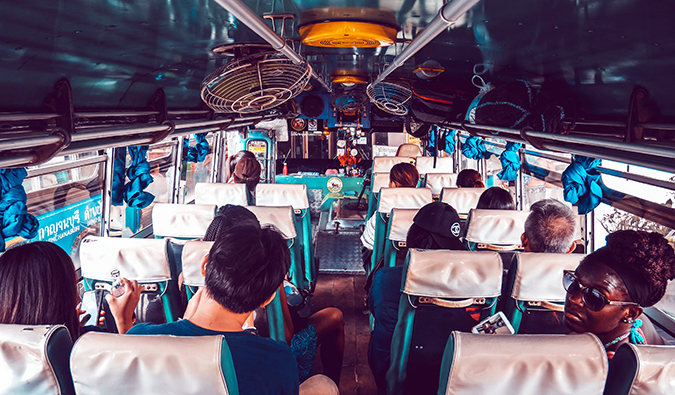 Pessoas a bordo de um ônibus lotado na Tailândia com ventiladores presos ao teto