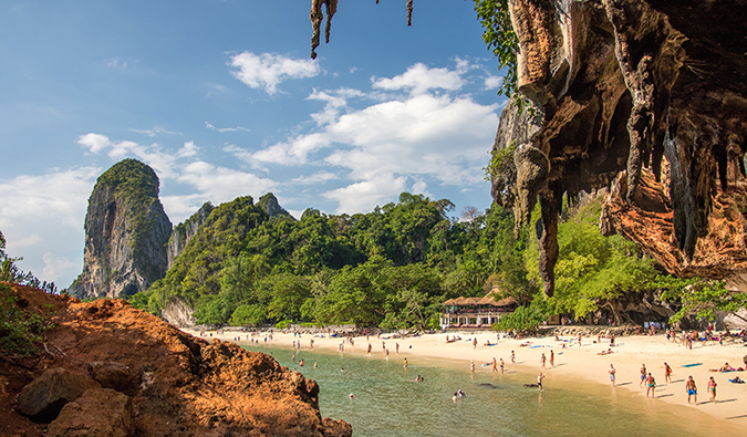 Vista de uma praia ensolarada na Tailândia emoldurada por afloramentos rochosos