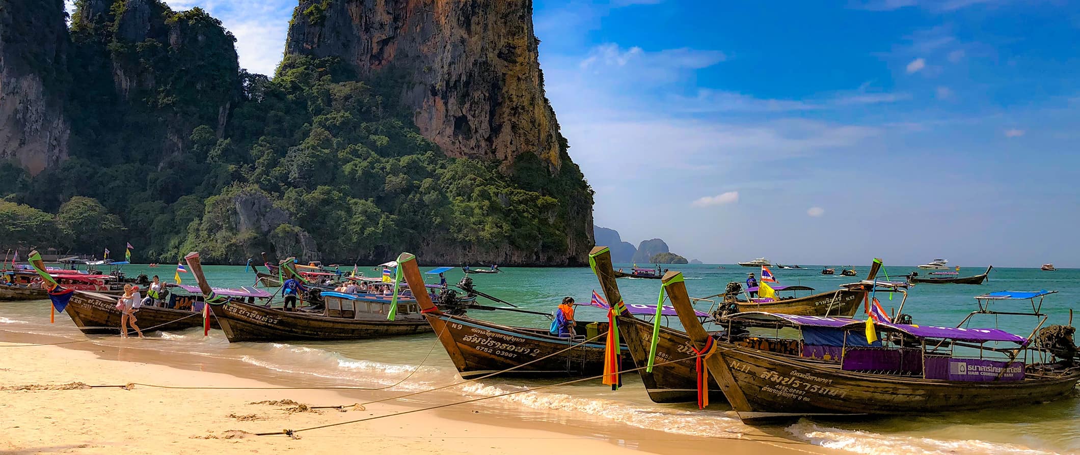Vários barcos longos estacionados em uma praia incrível na Tailândia
