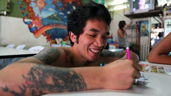 Tatsa local com tatuagens em um restaurante na Tailândia