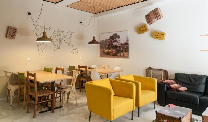 A zona comum eclética do albergue nômade com mesas de madeira e espreguiçadeiras amarelas brilhantes em Sevilha, Espanha