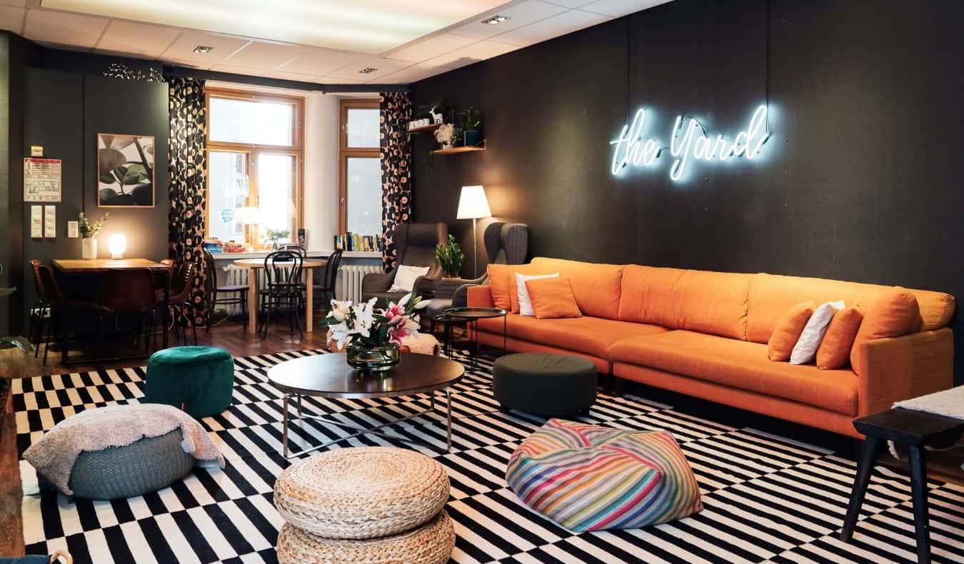 Linda sala comum em albergue em Helsinque, Finlândia, com um sofá de laranja, otomanos em que você pode sentar e inscrição de neon