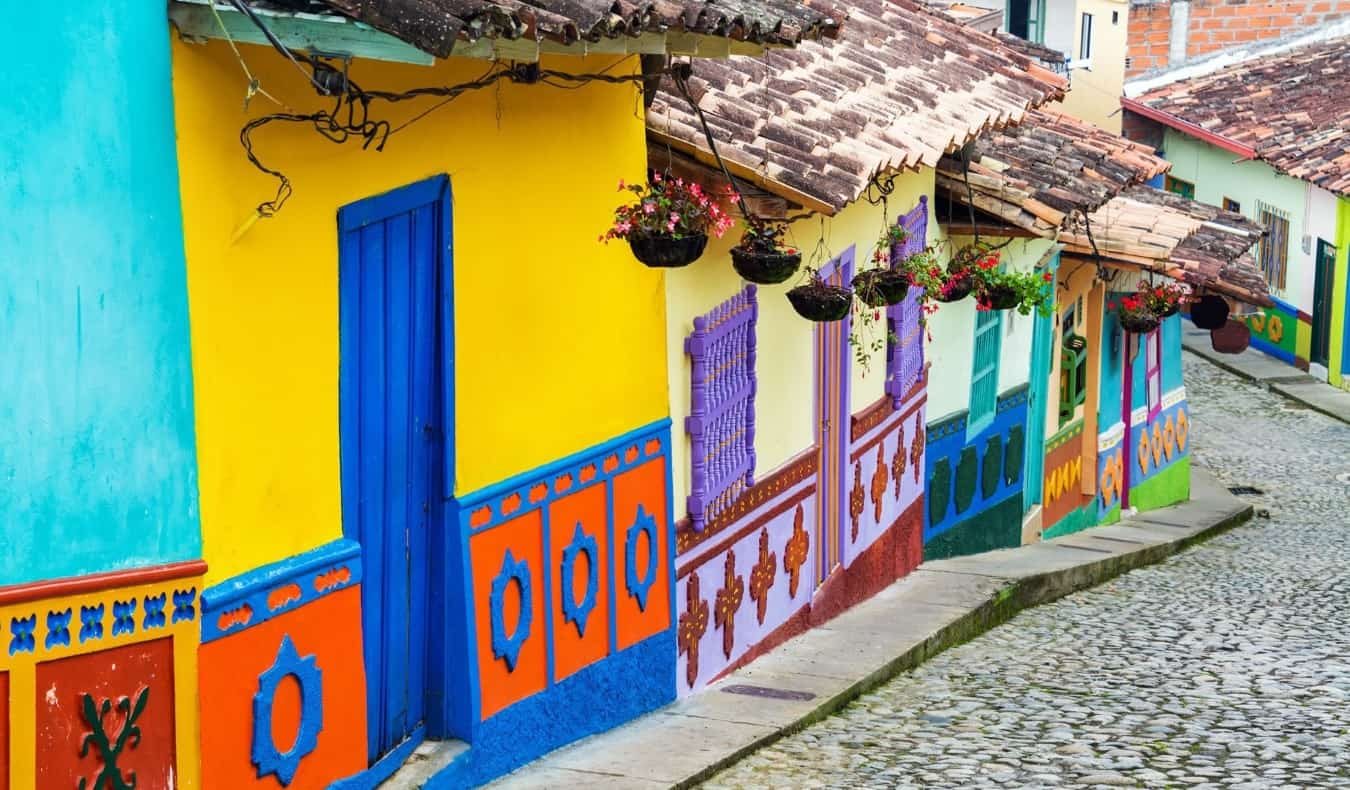 Casas mult i-coloridas em uma rua pavimentada montanhosa em Bogotá, Colômbia