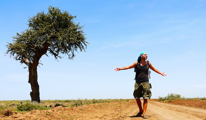 Tomislav, blogueiro e viajante do orçamento, fica ao lado da árvore solitária na Tanzânia, África