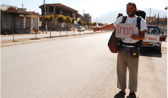 Mochila solitária, viajando de carona no Iraque com uma placa.