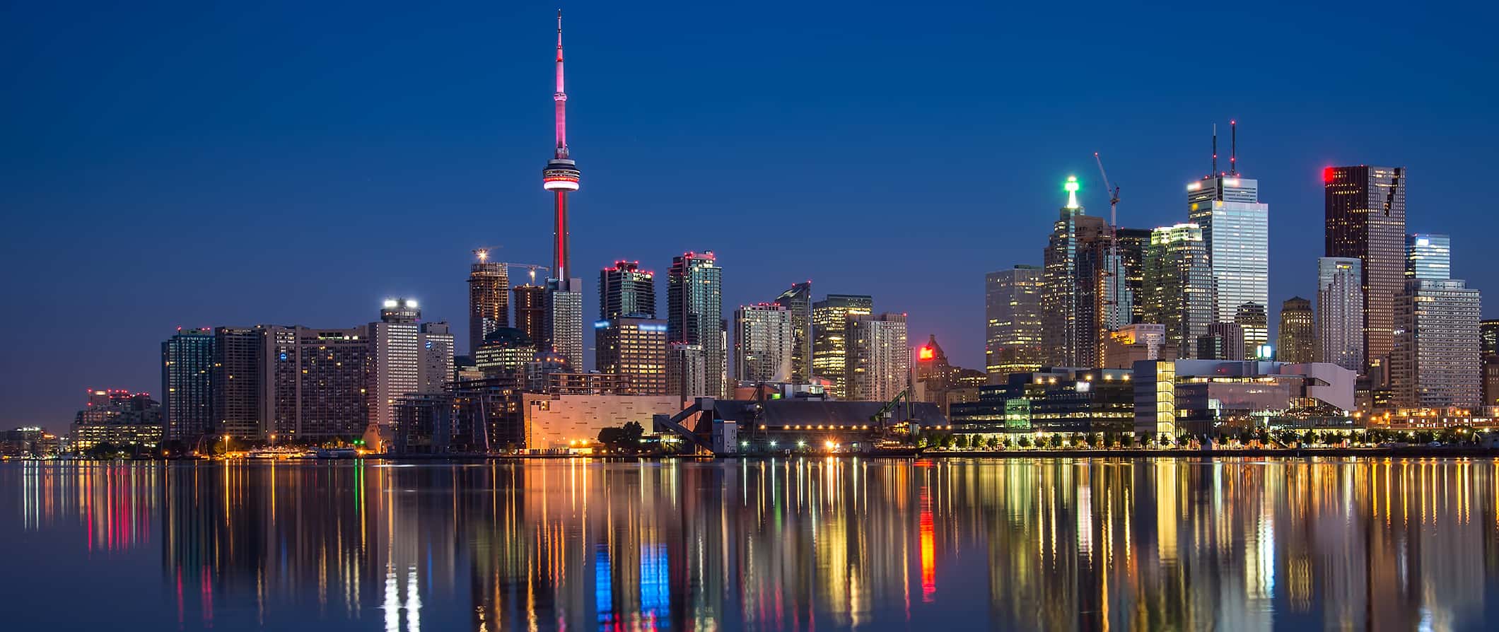 O horizonte noturno de Toronto, Canadá, refletiu nas águas calmas do lago Ontário.