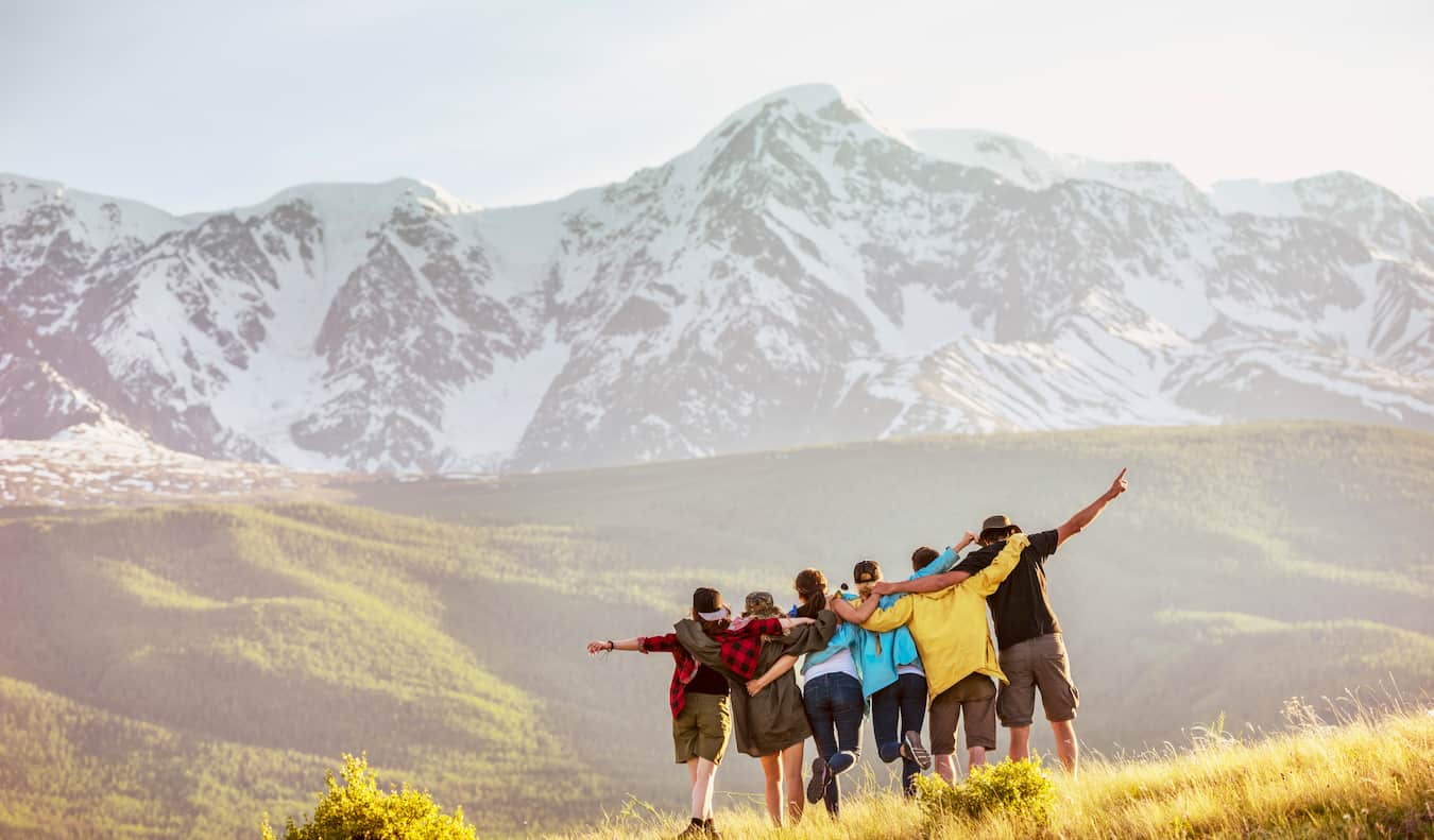 Um grupo de viajantes juntos faz uma caminhada nas montanhas em uma área intransitável, posando para uma foto.