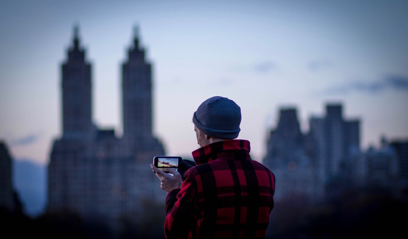 Um homem fotografa a cidade com um smartphone