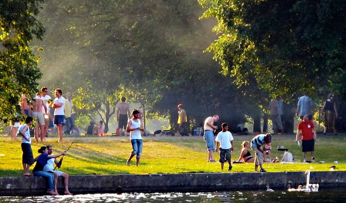As pessoas andam, conversam e pegam peixes nas margens do rio Spree em Treptauer Park, em Berlim, Alemanha