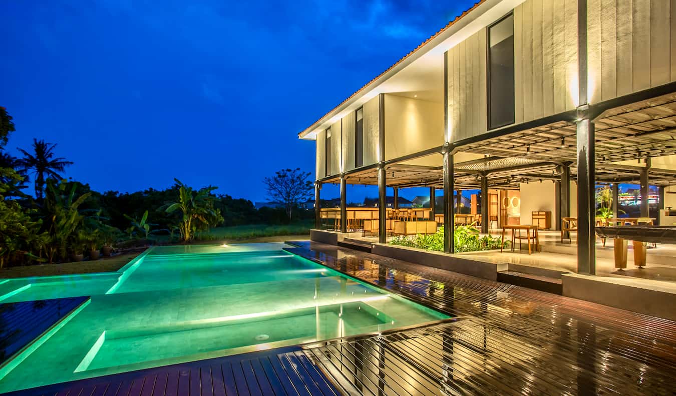 O exterior do Hostel Tribal Bali à noite com a piscina iluminada em primeiro plano