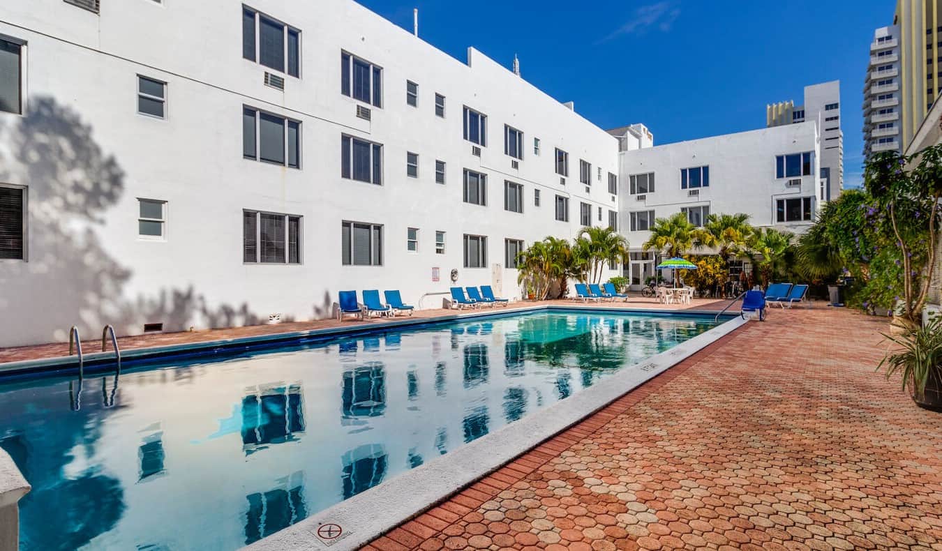 Uma longa piscina olímpica e um pátio repleto de ladrilhos no hotel e albergue The Tropics em Miami, Flórida
