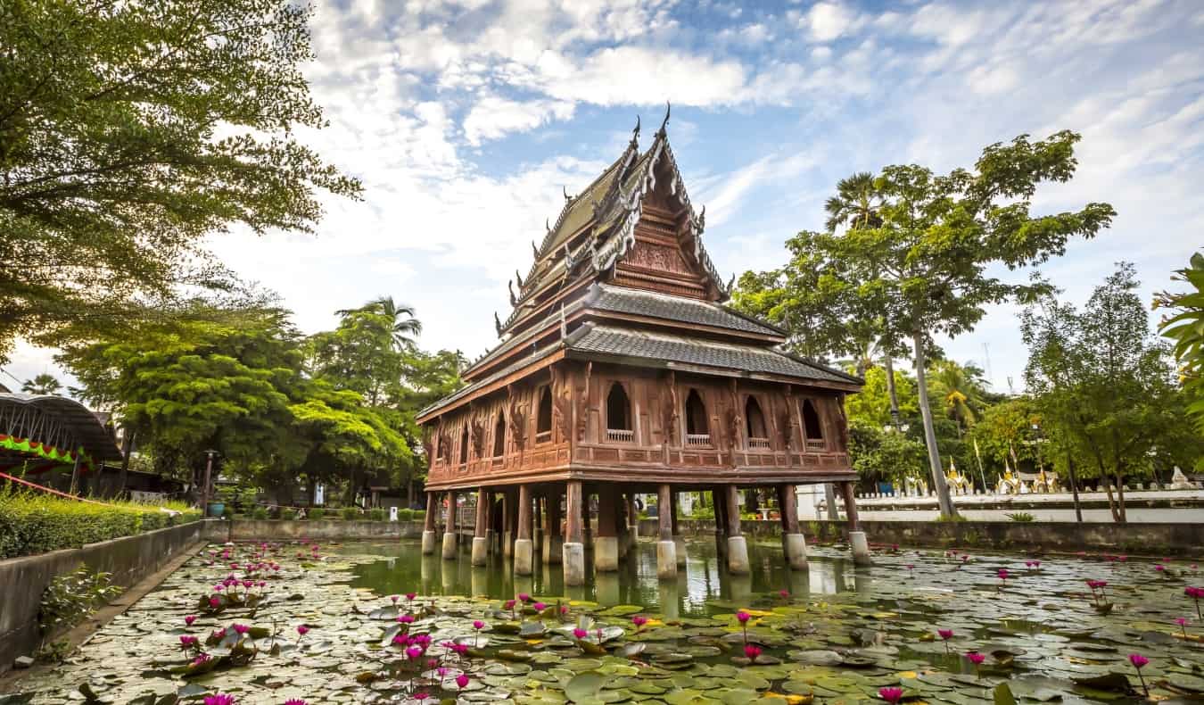 Templo budista brilhante em pilhas acima da lagoa com lótus no Rankathani Rankathana, Tailândia