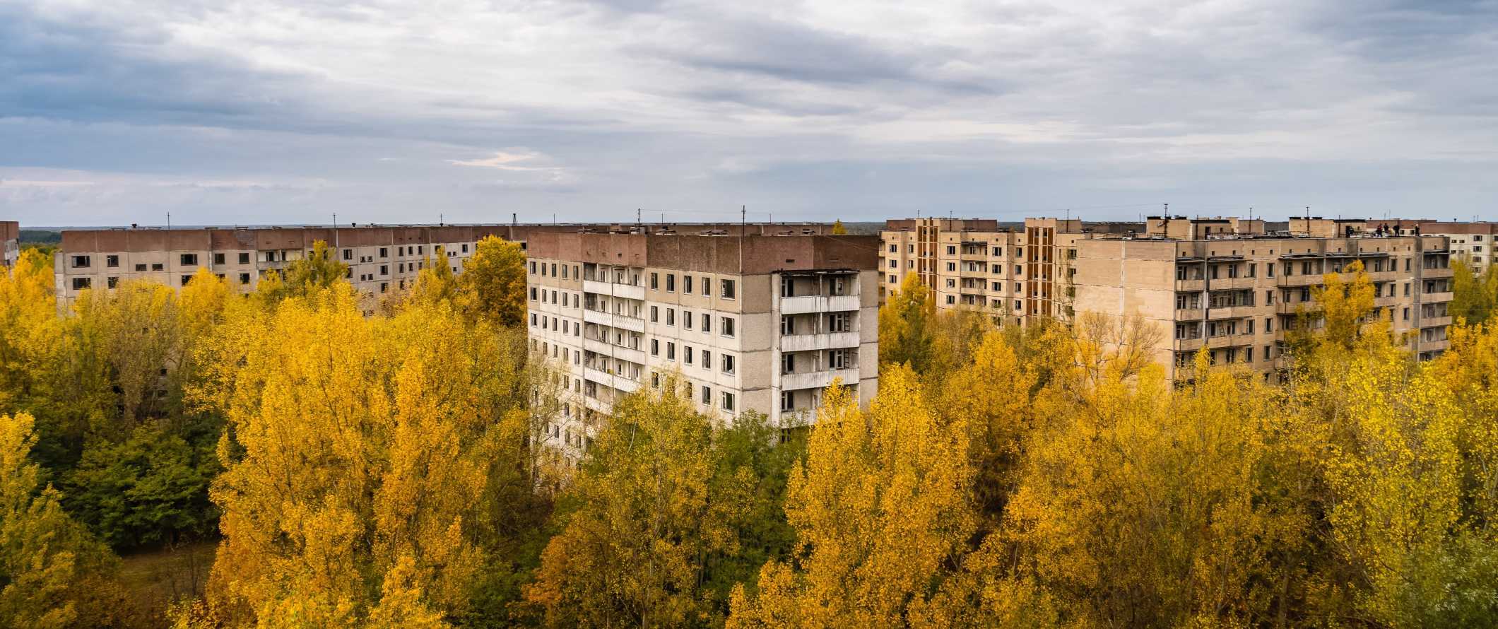 Vista de edifícios residenciais abandonados com árvores crescendo ao seu redor em Chernobyl, Ucrânia