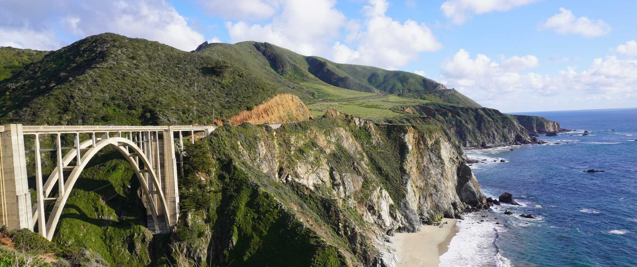 A ponte arqueada de Bixby-Krick ao longo da estrada da costa do Pacífico com colinas exuberantes ao fundo na Califórnia, EUA.