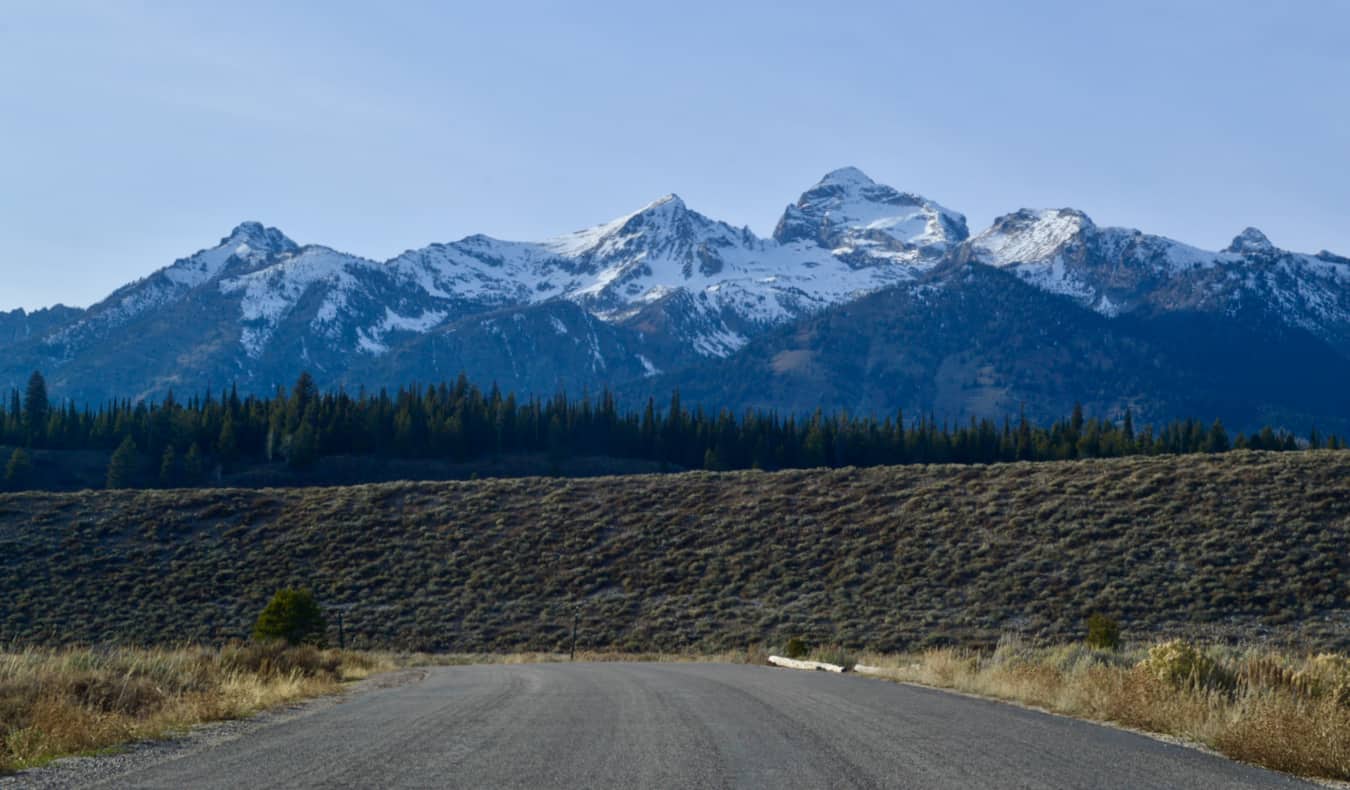 Uma estrada solitária em Vaiming, perto do Parque Nacional Grand Taton e suas montanhas nevadas