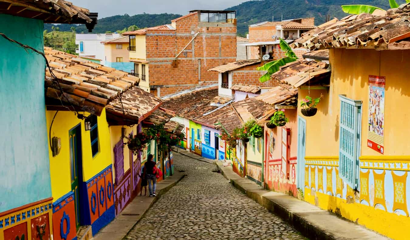 Rua vazia mult i-colorida na Colômbia, cercada por casas pintadas com cores vivas