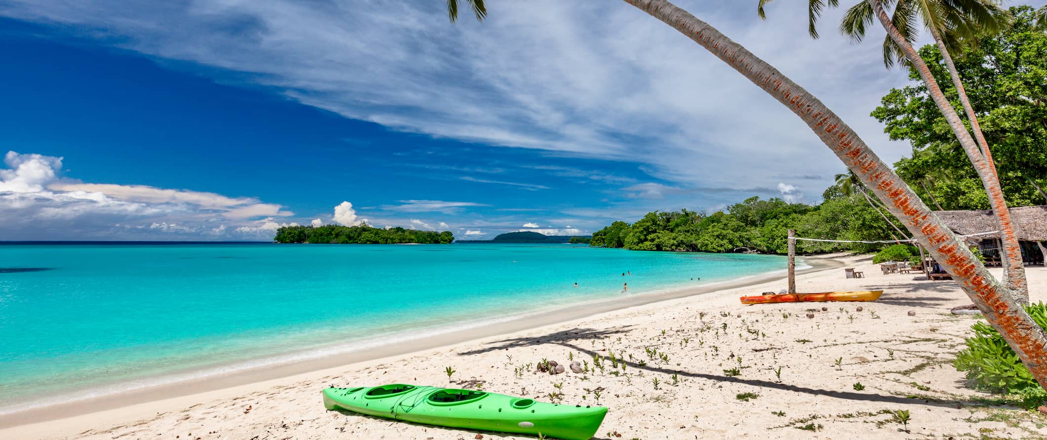 Praia de areia branca em Vanuatu com águas cristalinas e plantas tropicais emoldurando a vista