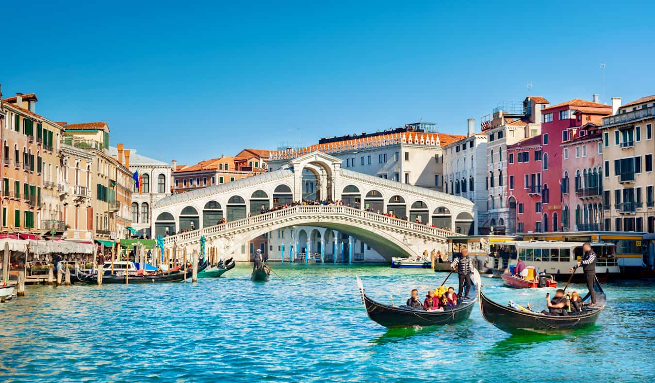 Dia ensolarado em Veneza, Itália, as pessoas andam de gôndolas através de grandes canais.