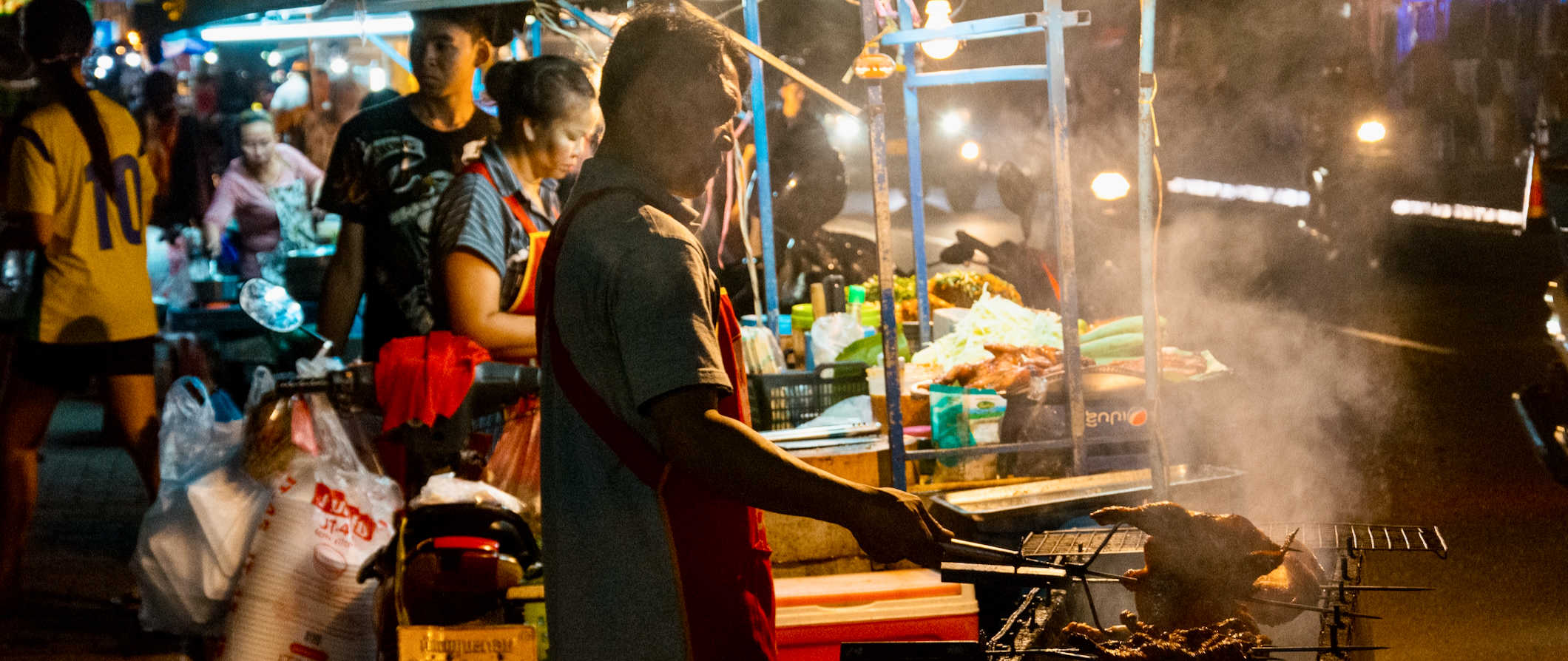 O vendedor local da Lao Street prepara comida no mercado noturno em Vienno, Laos