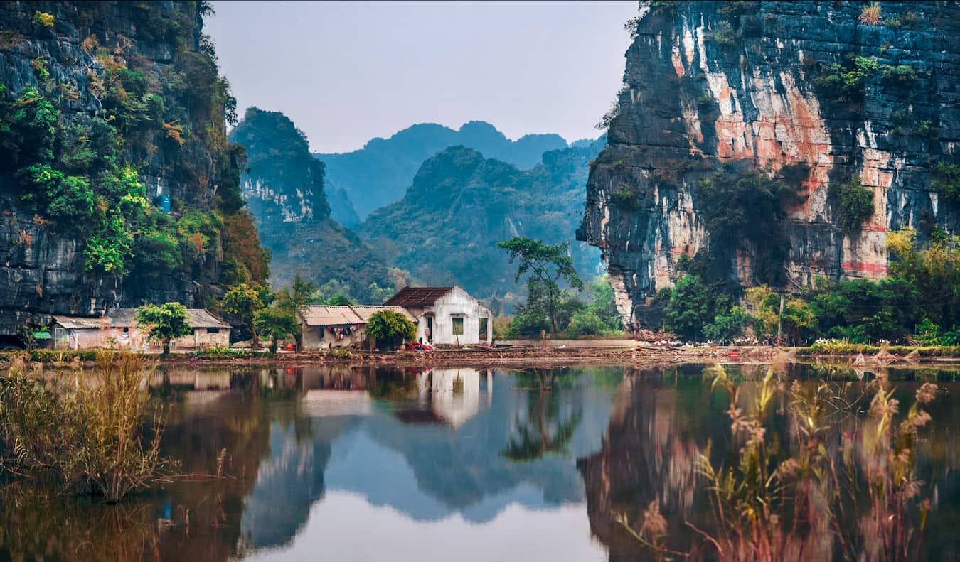 Um pequeno edifício situado em um cenário de montanhas à beira de um lago na zona rural do Vietnã