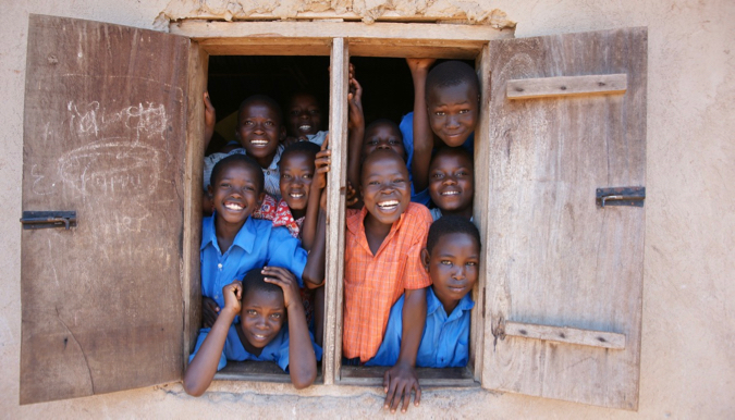 Sorrindo crianças em idade escolar na África olhando da janela da sala de aula
