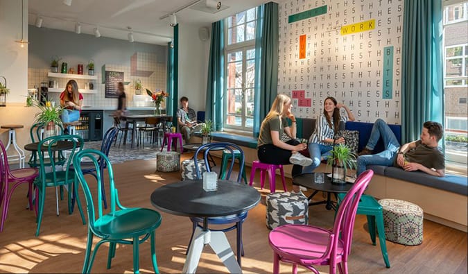 As pessoas passam um tempo em uma zona comum com mesas redondas e cadeiras brilhantes em Stayokay Amsterdã Vondelpark