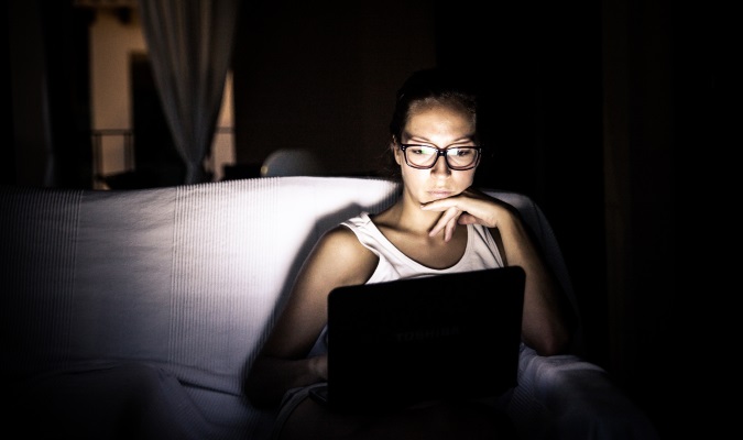 Uma mulher que viajador de mulher usa seu laptop no escuro