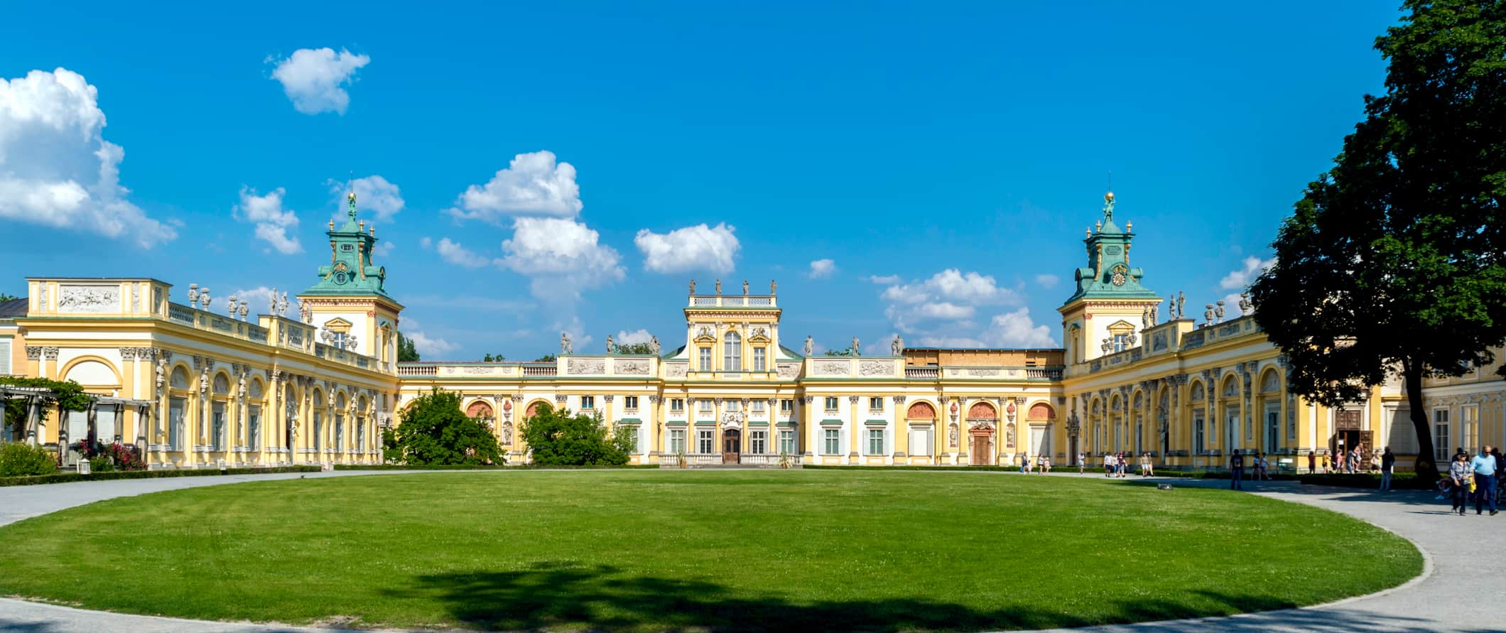 Amplo palácio real cercado por grama verde em um dia ensolarado em Varsóvia, Polônia