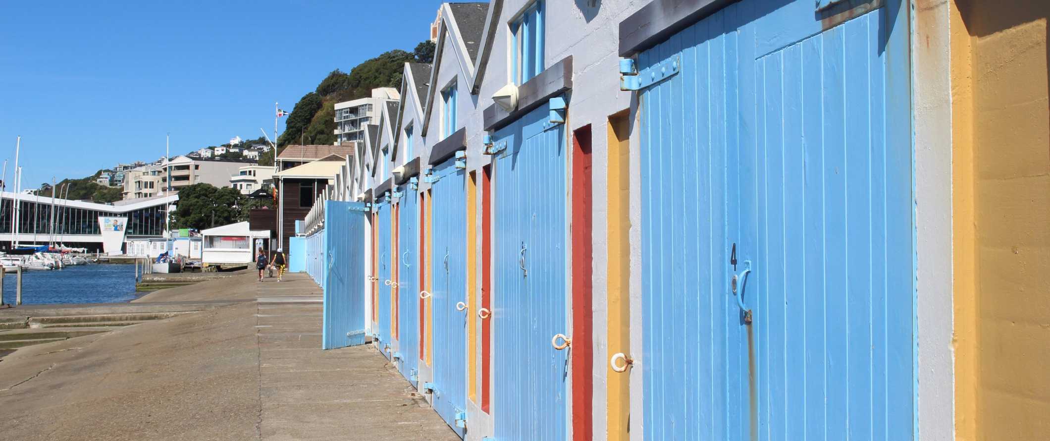 Barcos pintados em cores vivas e armazéns alinham-se à beira-mar do porto em Wellington, Nova Zelândia.