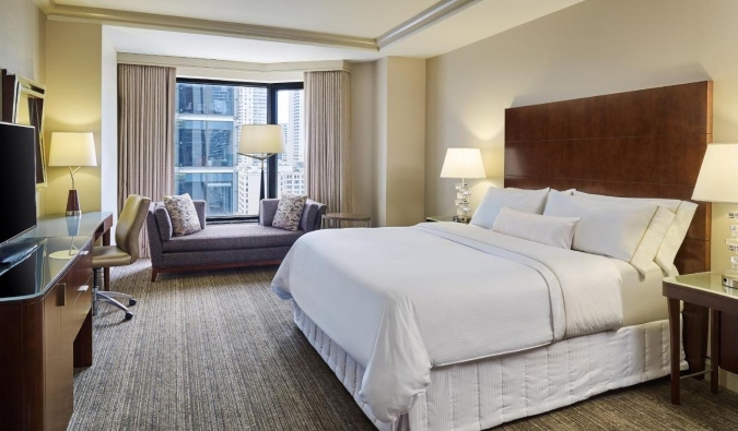 Uma cama king-size branca em um quarto simples, mas moderno, com vista para o Westin Chicago River North