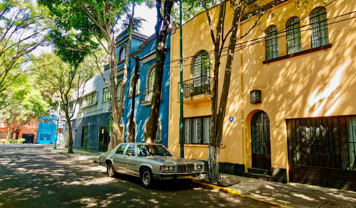 Rua tranquila com casas coloridas em Condesa, Cidade do México, com um carro estacionado na rua