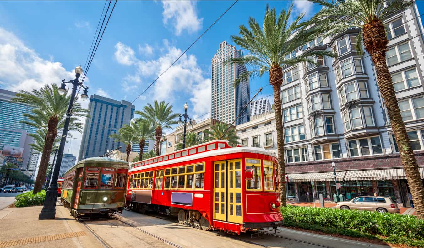 Tram vermelho brilhante viaja ao longo do ensolarado Nova Orleans, EUA