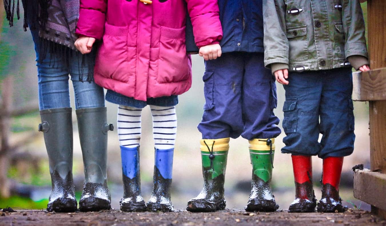 Uma au pair fica com crianças com botas de chuva na lama