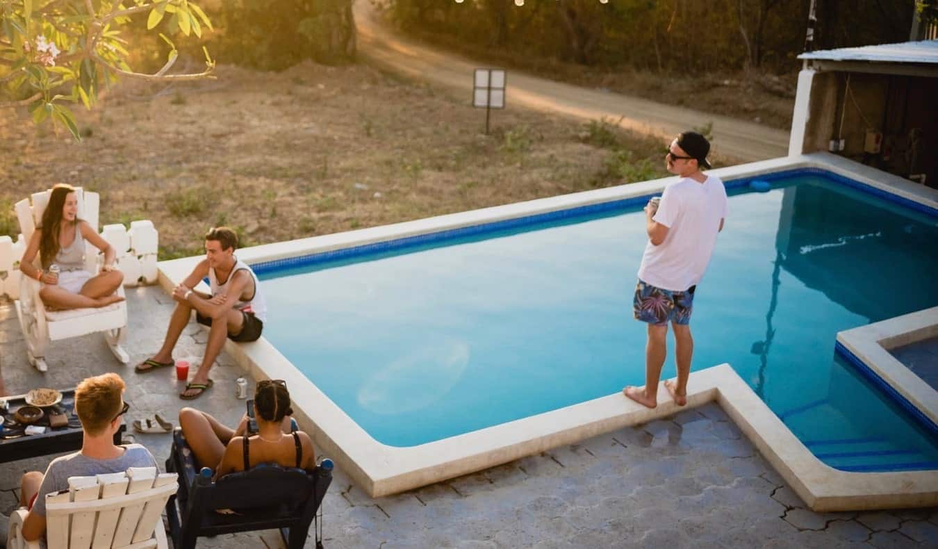 Grupo de viajantes relaxando à beira da piscina em um albergue no exterior